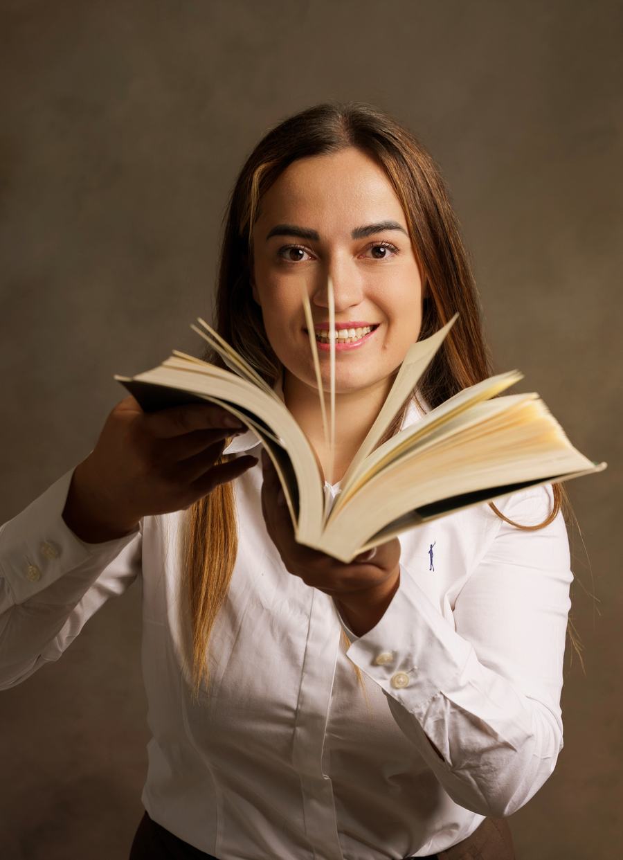Raquel Vicente-Ruiz sonriendo con un libro abierto